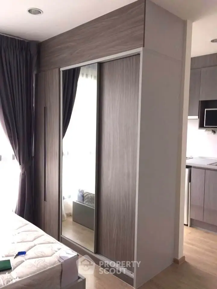 Modern bedroom with built-in wardrobe and partial kitchen view