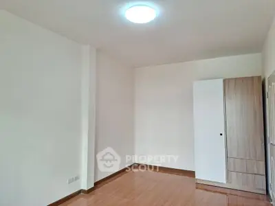 Spacious empty room with wooden flooring and modern wardrobe, ideal for customization.