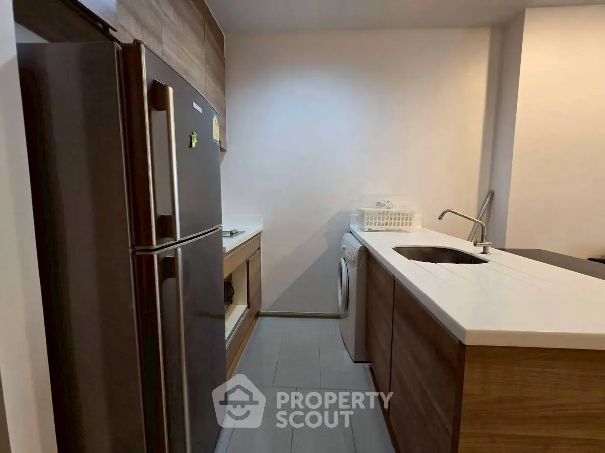 Modern kitchen with sleek appliances and compact layout, featuring a washing machine and stylish cabinetry.