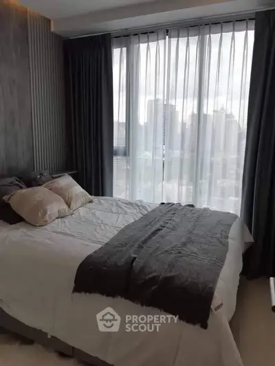 Modern bedroom with city view, featuring cozy bedding and floor-to-ceiling windows.