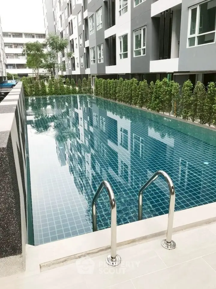Modern condominium with a pristine swimming pool and lush greenery.