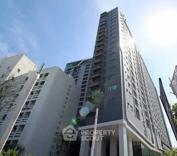 Modern high-rise building with sleek design and sunny sky backdrop.