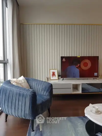 Modern living room with stylish blue armchair and wall-mounted TV