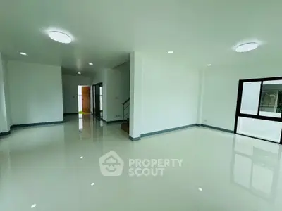 Spacious modern living room with glossy tiled floors and ample natural light.