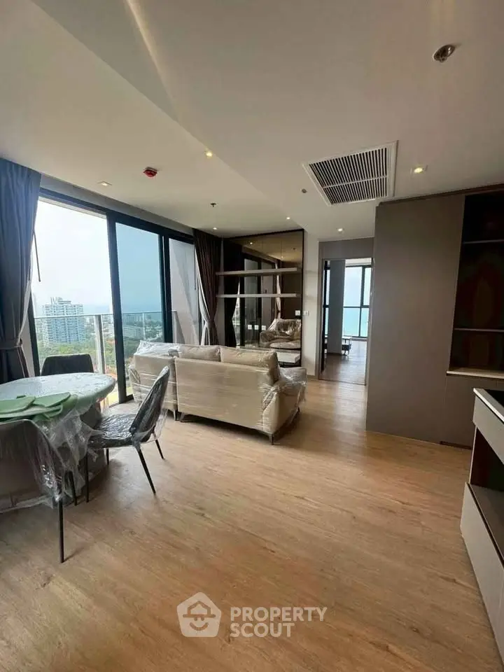 Spacious modern living room with large windows and city view, featuring stylish furniture.