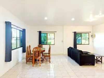 Spacious living room with tiled floor, wooden dining set, and cozy black sofa.