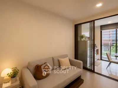 Cozy living room with sliding glass doors leading to a bright dining area, featuring a plush sofa and modern decor.