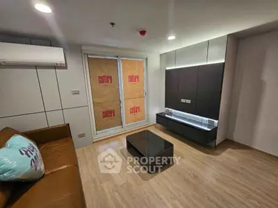 Modern living room with sleek design, featuring a brown leather sofa, air conditioning, and stylish cabinetry.