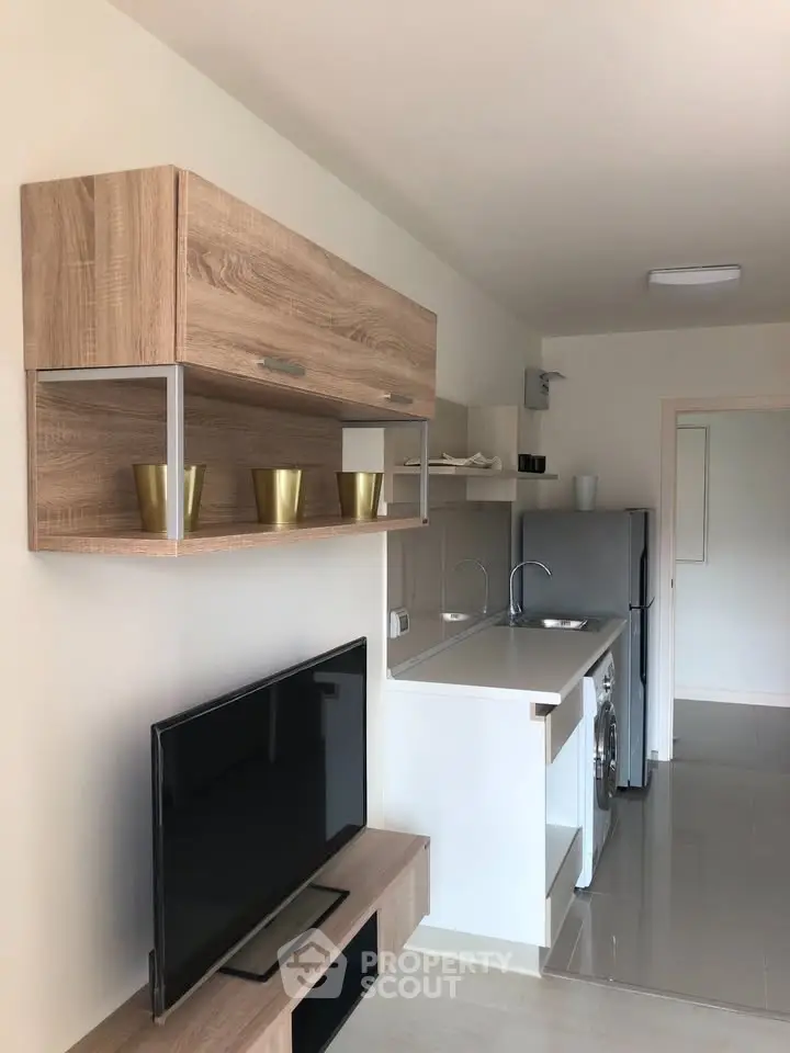 Modern studio apartment with sleek kitchen and stylish wooden shelving, perfect for urban living.