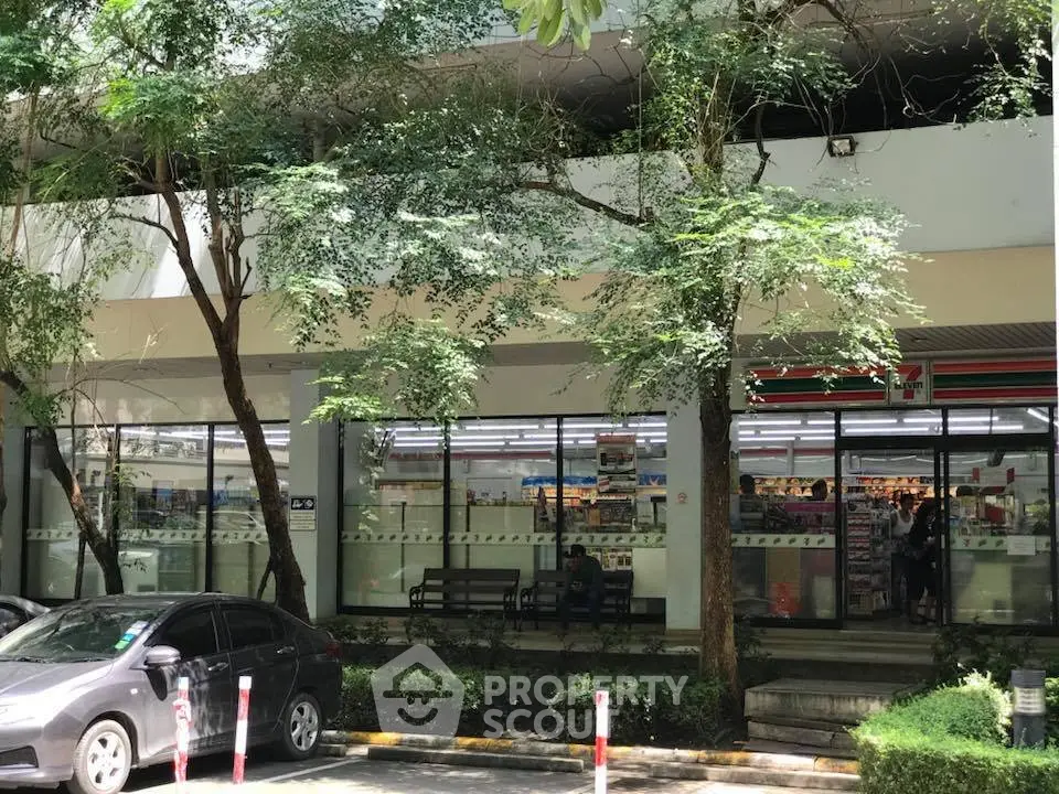 Street-level view of a commercial building with a convenience store and parking area.