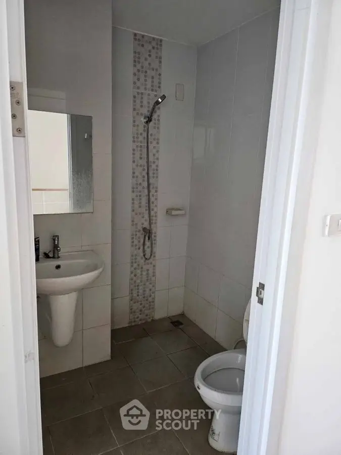 Compact bathroom with shower and modern fixtures in a minimalist design.