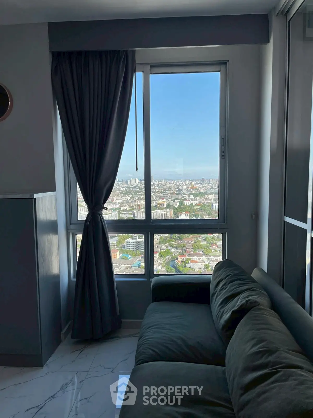 Modern living room with panoramic city view from high-rise window.