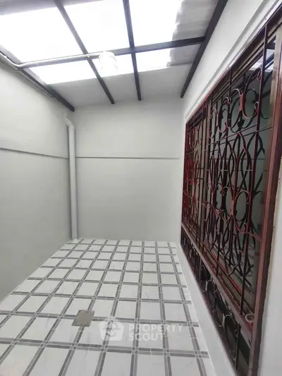 Modern enclosed balcony with tiled floor and decorative window grille