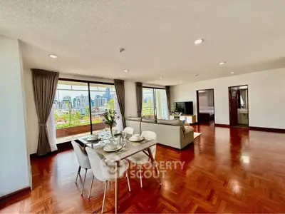 Spacious open-plan living room with dining area and city view balcony in modern apartment.