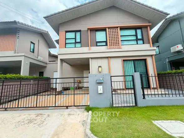 Modern two-story house with a gated driveway and manicured lawn in a suburban neighborhood.