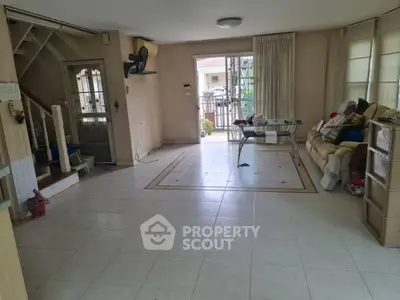 Spacious living room with tiled flooring and natural light in a cozy home.