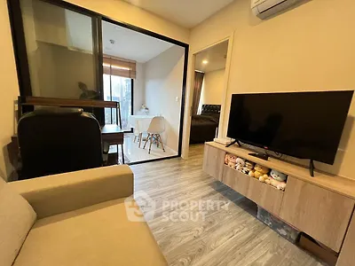 Modern living room with TV, cozy sofa, and dining area in open layout apartment.