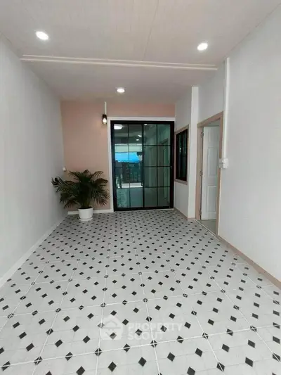 Spacious tiled entrance with glass doors and potted plant, ideal for modern living.