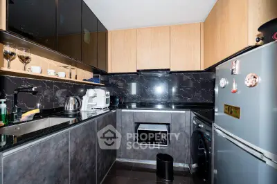 Modern kitchen with sleek black countertops and wooden cabinets, featuring stainless steel appliances and stylish decor.