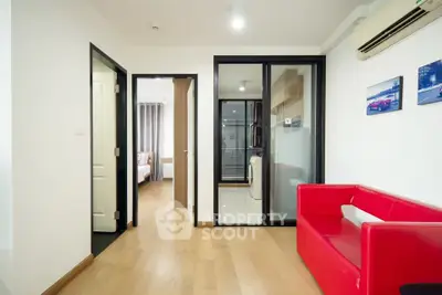 Modern apartment interior with red sofa and wooden flooring, showcasing a bright and inviting living space.