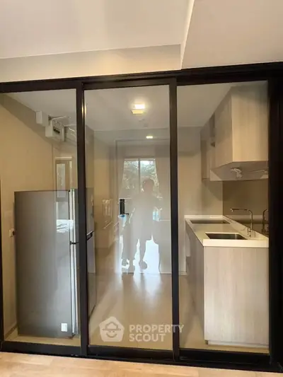 Modern kitchen with sleek design and glass sliding doors, featuring built-in appliances and ample natural light.
