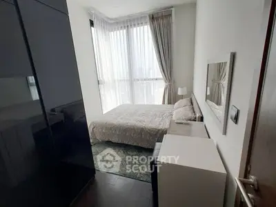 Cozy modern bedroom with large windows and elegant decor in a high-rise apartment.