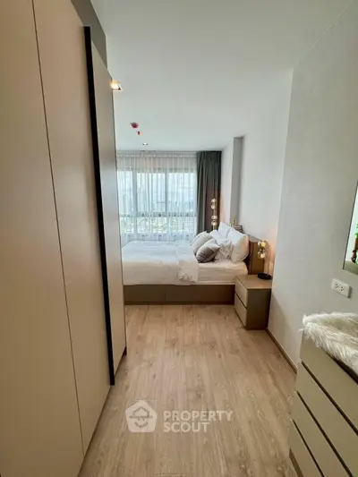 Modern bedroom with large window and stylish decor in a high-rise apartment.