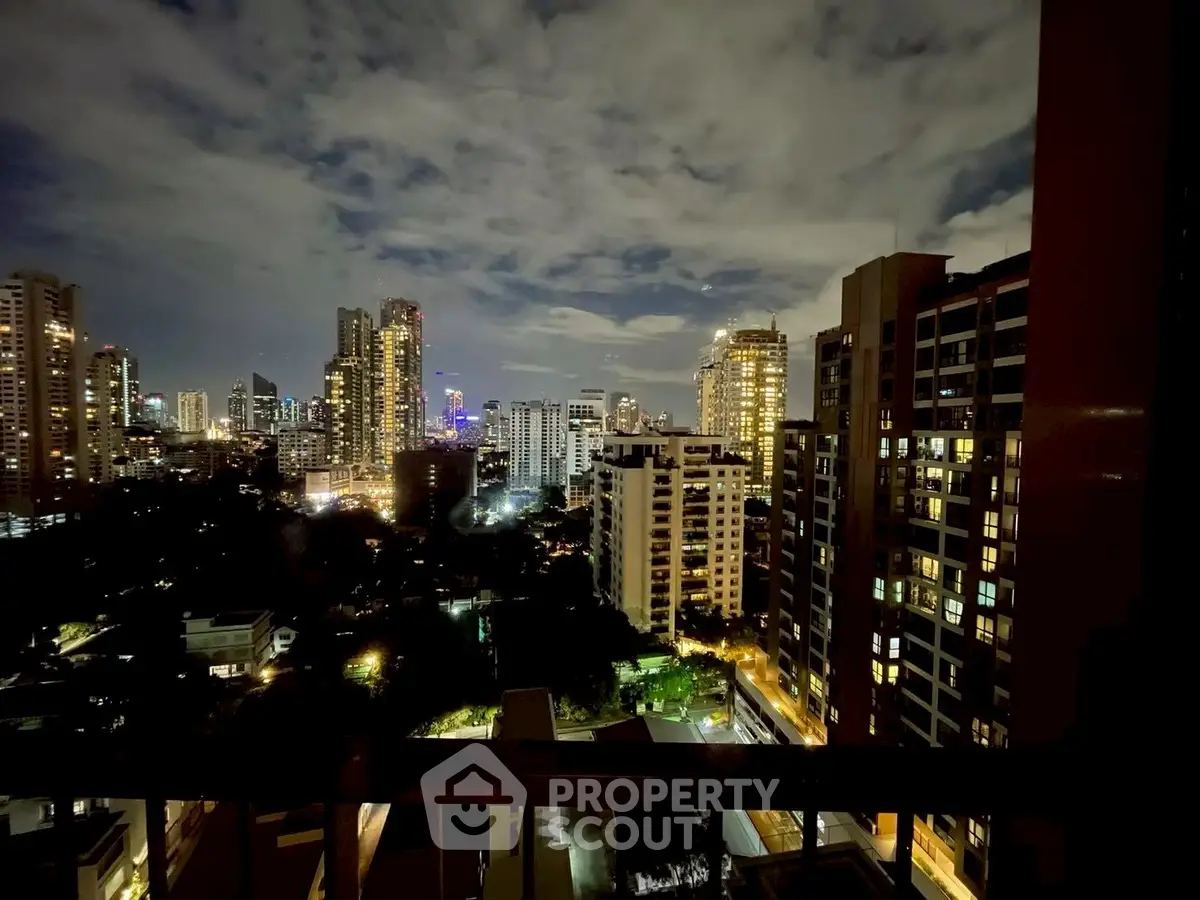 Stunning city skyline view from a high-rise balcony at night, showcasing vibrant urban lights.
