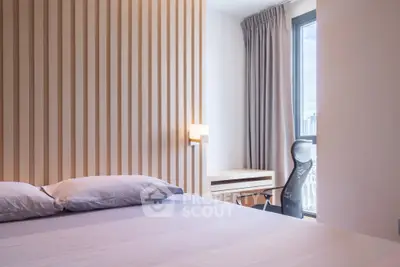 Modern bedroom with stylish decor and city view, featuring a comfortable bed and a sleek office chair.