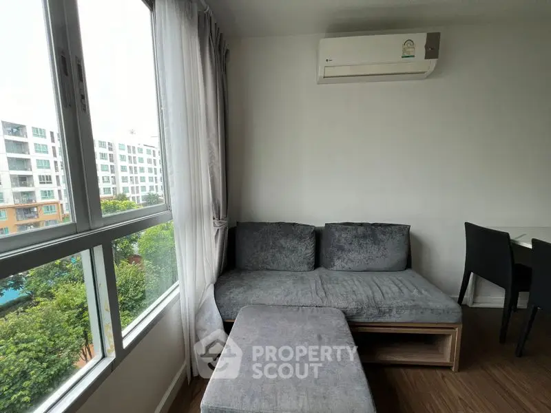 Modern living room with cozy gray sofa and large window view in a stylish apartment.