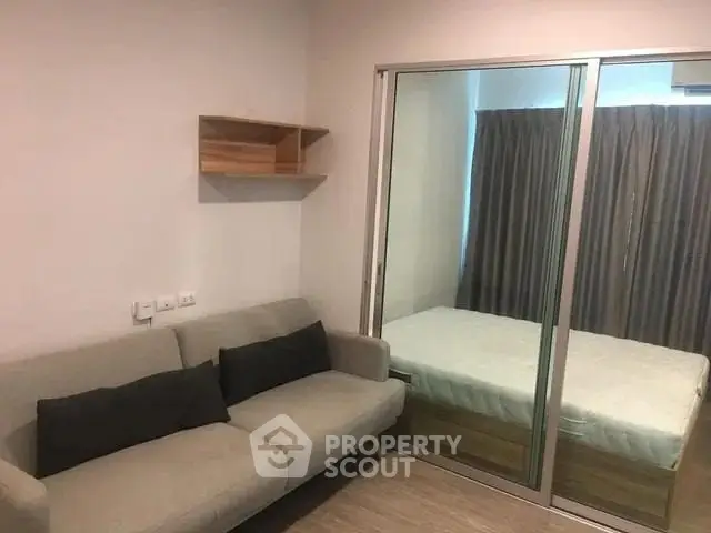 Cozy bedroom with mirrored sliding doors and a comfortable sofa, perfect for modern living.
