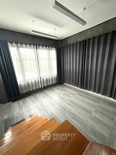 Spacious room with large windows and modern curtains, perfect for natural light and privacy.