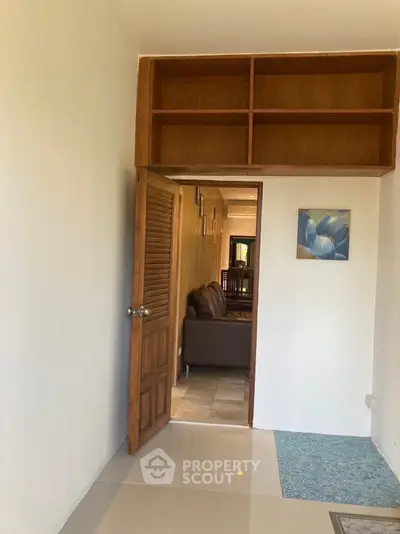 Spacious interior with wooden door and built-in shelves, leading to a cozy living area.