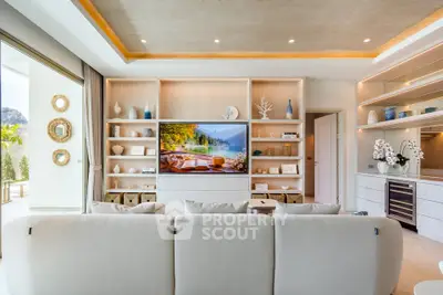Luxurious living room with elegant decor and large TV, opening to a spacious balcony with scenic views.