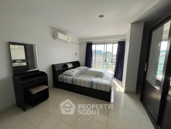 Spacious bedroom with modern furnishings and large window offering natural light and scenic views.