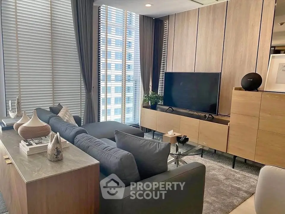 Modern living room with sleek furniture and large windows offering city views.