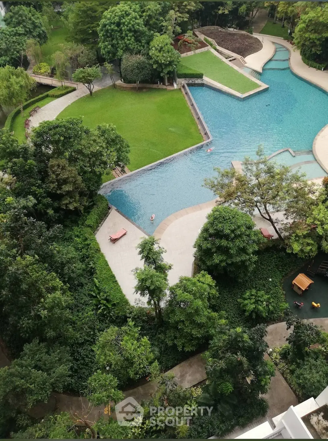 Luxurious aerial view of a serene pool and lush garden in a high-end residential complex.