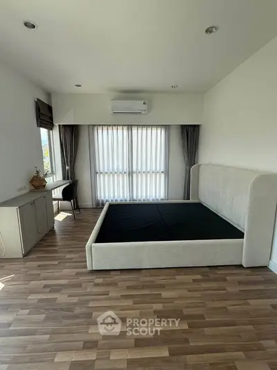 Spacious bedroom with modern decor and large windows for natural light