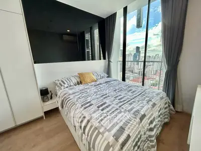 Modern bedroom with large windows offering stunning city views and stylish decor.