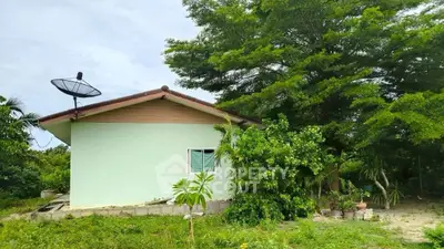 Charming single-story home with lush greenery and satellite dish in serene setting.