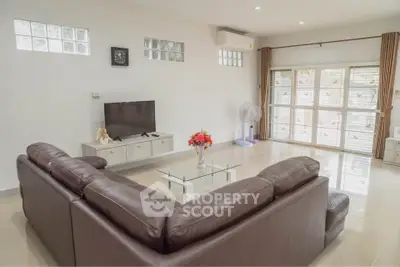 Spacious living room with modern leather sofa and large windows for natural light.