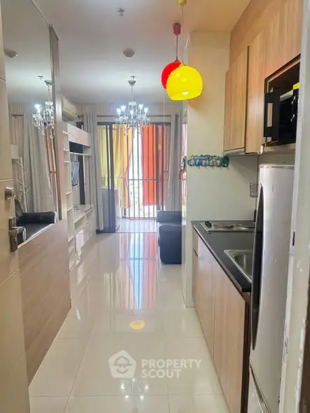 Modern apartment interior with sleek kitchen and bright living area, featuring colorful pendant lights.