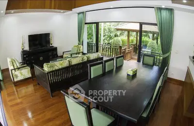 Spacious living room with elegant dining area and garden view, featuring stylish furniture and wooden flooring.