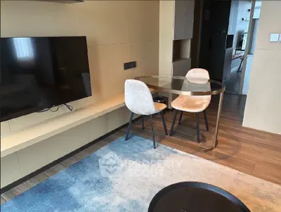 Modern living room with wall-mounted TV and stylish dining area in open layout apartment.