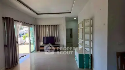 Spacious living room with modern TV setup and large windows for natural light.