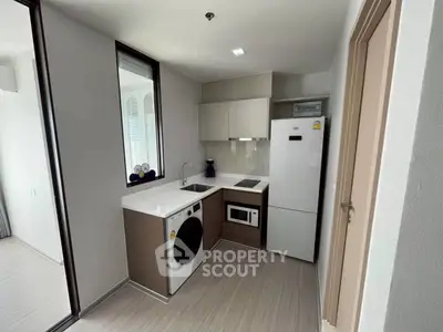 Modern compact kitchen with sleek appliances and stylish cabinetry in a contemporary apartment.