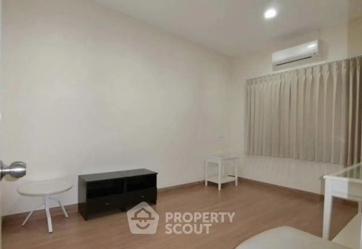 Minimalist room with air conditioning and wooden flooring, ideal for versatile use.