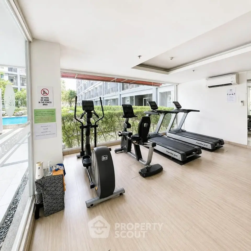 Modern gym with state-of-the-art equipment and pool view in luxury apartment complex.