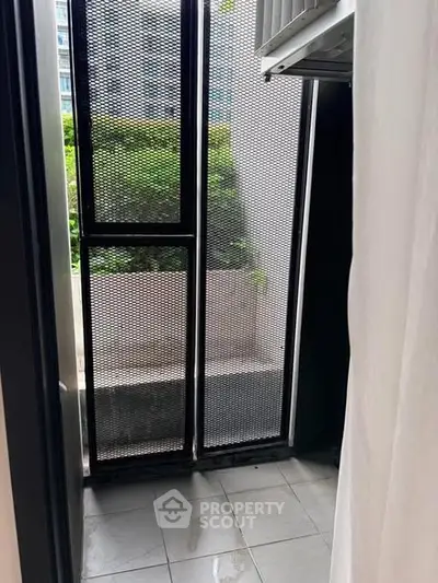 Compact balcony with metal mesh screen and garden view, ideal for urban living.
