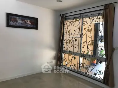 Bright room with decorative window grill and elegant curtains, perfect for cozy living space.